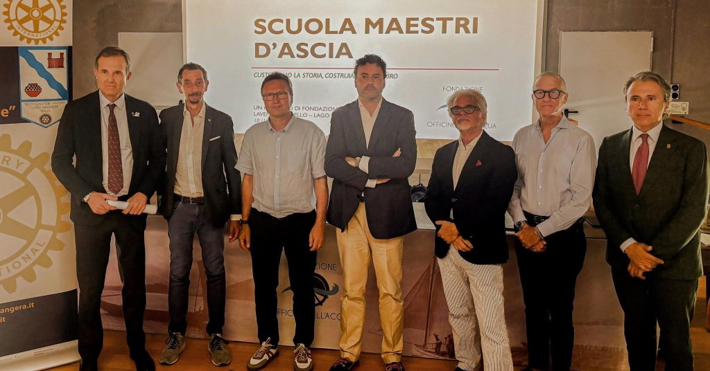 Gruppo di persone in piedi di fronte a uno schermo con il testo 'Scuola Maestri d'Ascia'.
