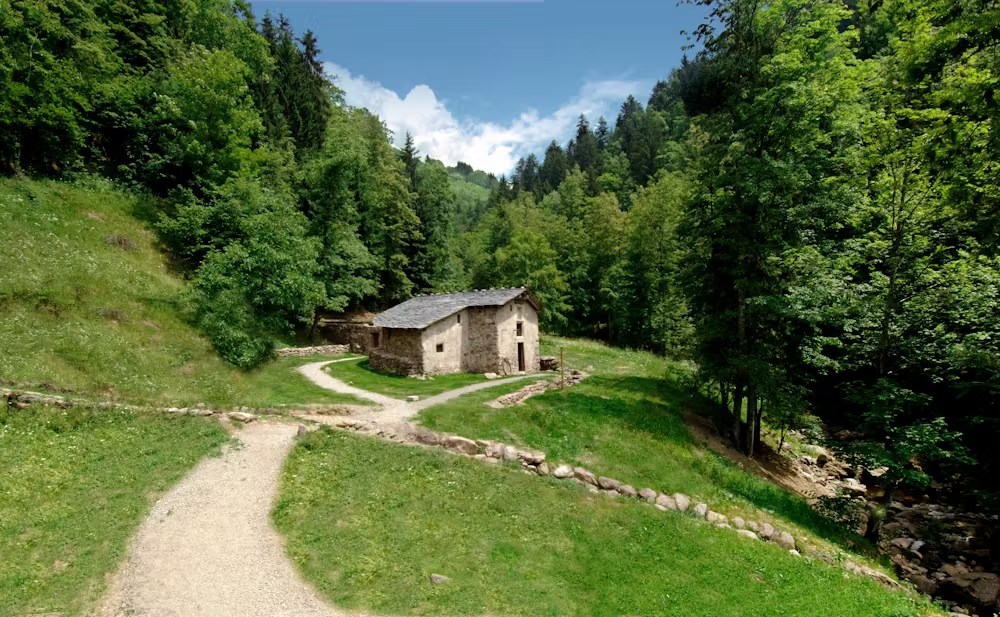 Una casa rustica circondata da alberi verdi e sentieri di ghiaia in una valle