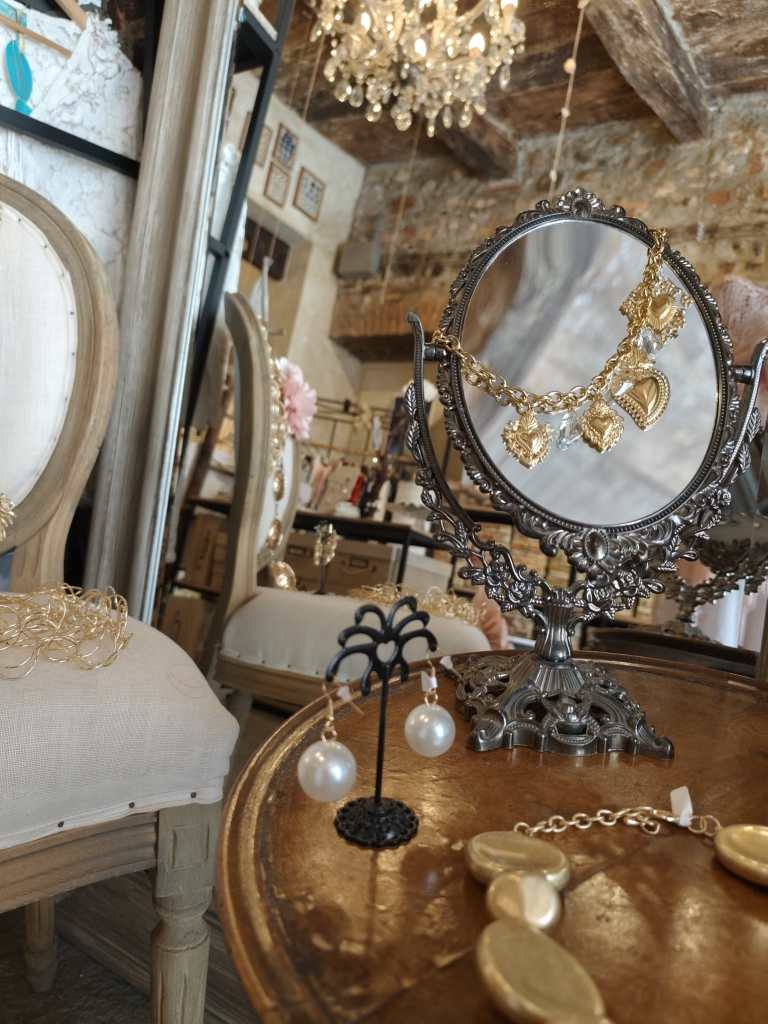 Negozio di gioielli con lampadario decorativo; collana e orecchini in evidenza su una superficie di legno.
